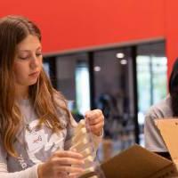 Two students loading packaged string cheese into a box